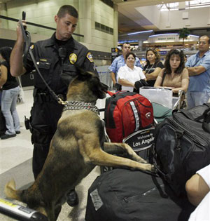 Los Angeles Airport Police officer Michael Manahan guides his dog, Baso, to check luggage as travelers wait in line at Los Angeles International Airport Los Angeles Airport Police officer Michael Manahan guides his dog, Baso, to check luggage as travelers wait in line at Los Angeles International Airport